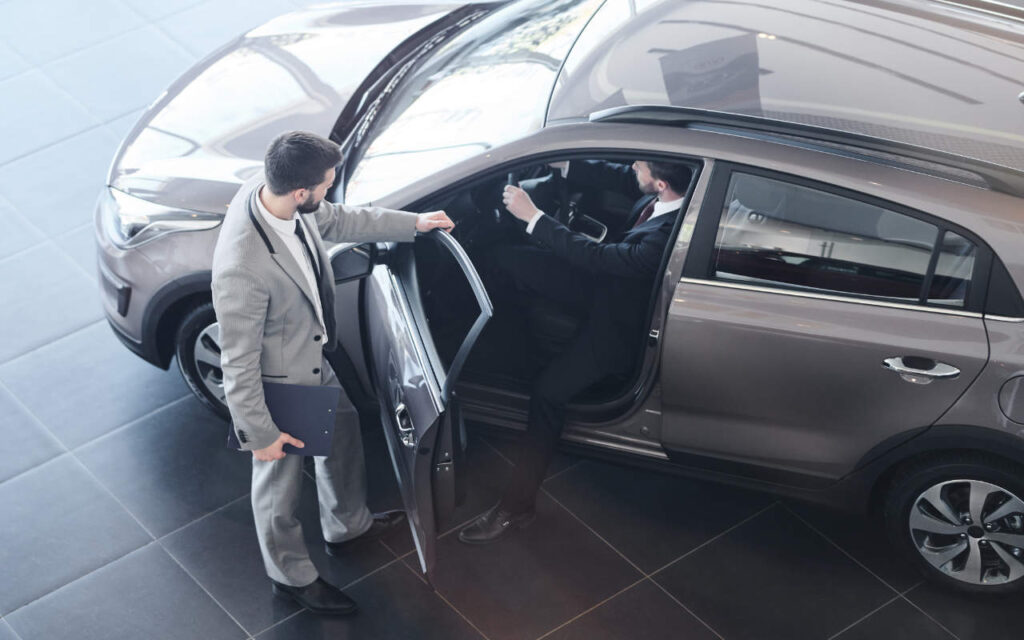man in grey suit opens car door for a driver who is considering getting a car with the car leasing benefit scheme.