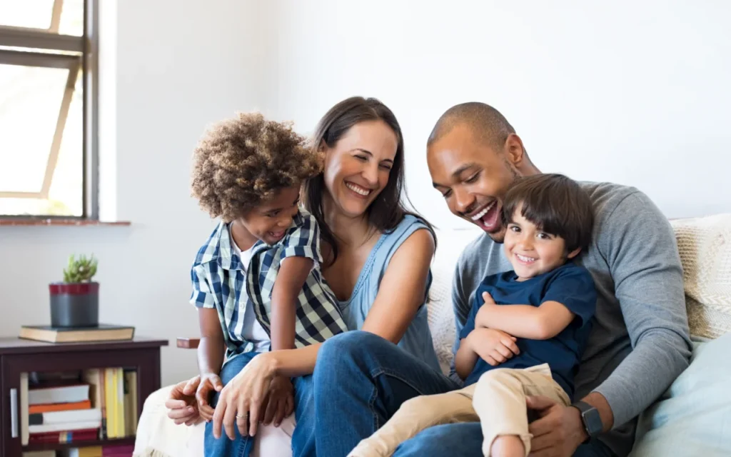 a family sit on the sofa, laughing together