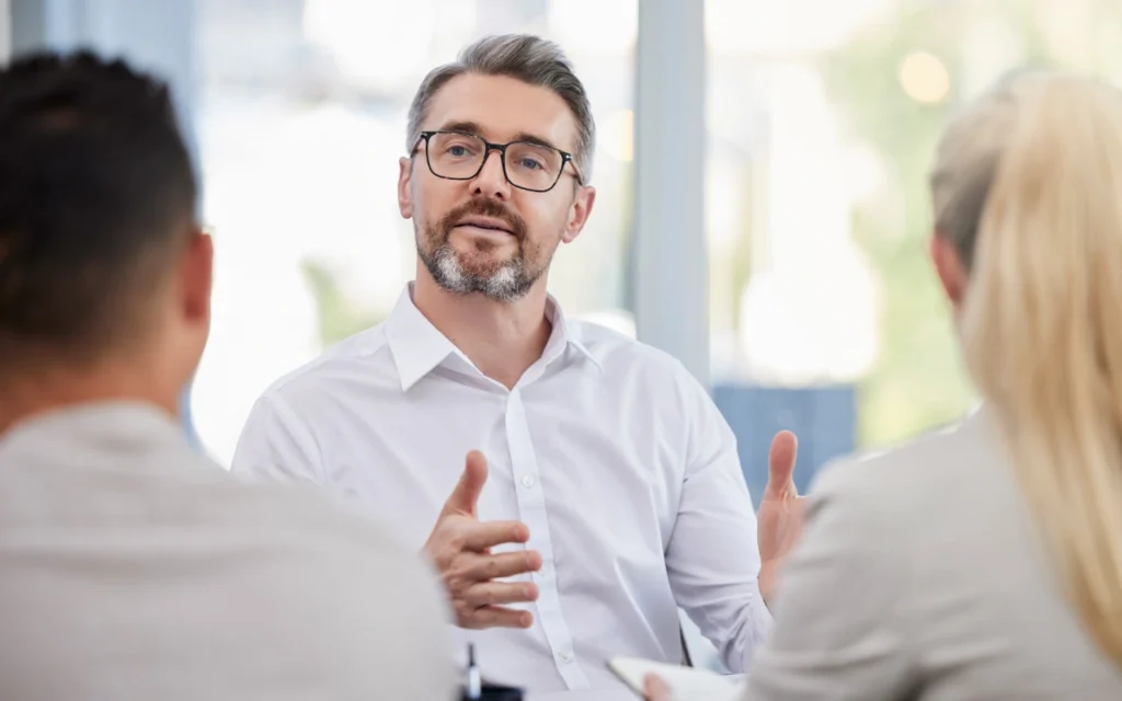 man sitting in front of two others explaining something
