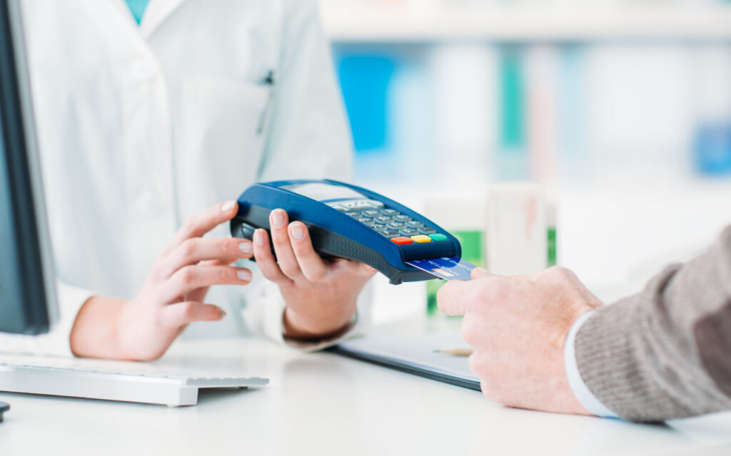 A man placing a credit card into a crd reader at a doctor's surgery reception
