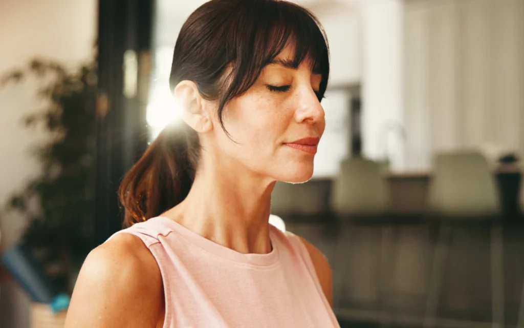A woman with her eyes closed concentrating on her breathing to combat stress and anxiety